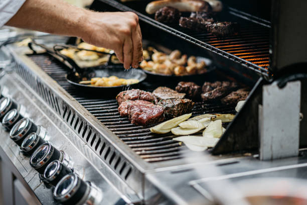 mão humana adiciona sal aos bifes na churrasqueira - grilled - fotografias e filmes do acervo