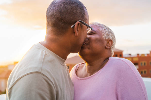 szczęśliwa latynoska para seniorów mająca romantyczną chwilę całowania się na dachu podczas zachodu słońca - starsi ludzie kochają koncepcję - couple black american culture kissing zdjęcia i obrazy z banku zdjęć