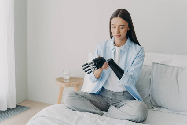 istock Disabled young girl disassembles bionic prosthetic arm, sitting on bed at home. Medical technologies 1445187341