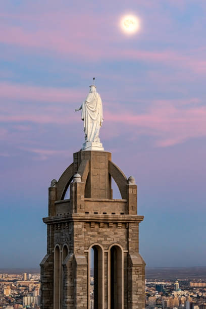 Santa Cruz Chapel tower and the virgin Mary statue Aerial view of the back sculpture from behind looking at a full moon and the city of Oran with a colorful cloudy sky, blue hour sunset twilight. oran algeria photos stock pictures, royalty-free photos & images