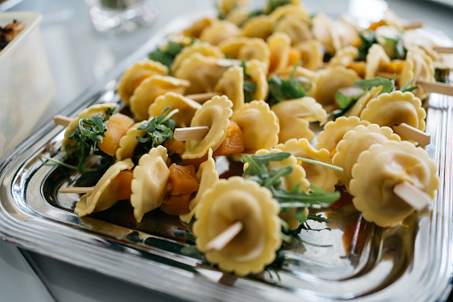 tortellini skewers with pumpkin and arugula served on a sliver plate