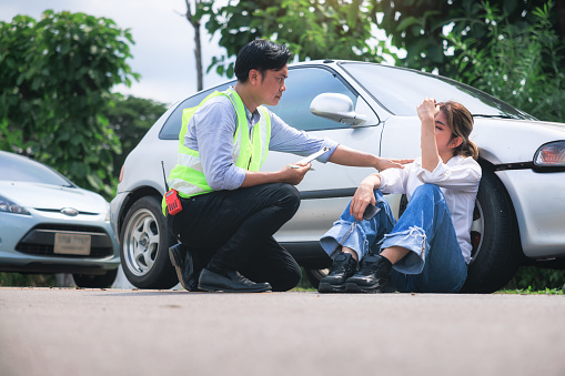 Accident, crash or collision of auto car, bicycle at outdoor. Include asian people i.e. insurance officer man to examining, write document report and young girl or bicycle rider to injury on road. Concept for vehicle crash, insurance claim, emergency and safety.