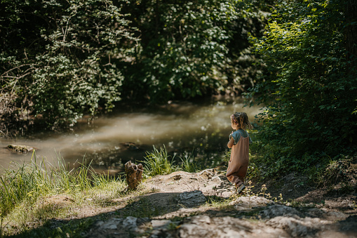 Cute little girl playing in fresh mountain stream in the wilderness on sunny day