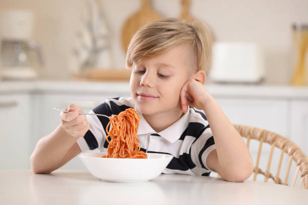 istock Happy boy eating tasty pasta at table in kitchen 1445191787