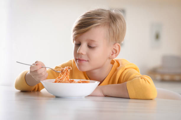 istock Cute boy eating tasty pasta at table in kitchen 1445191789