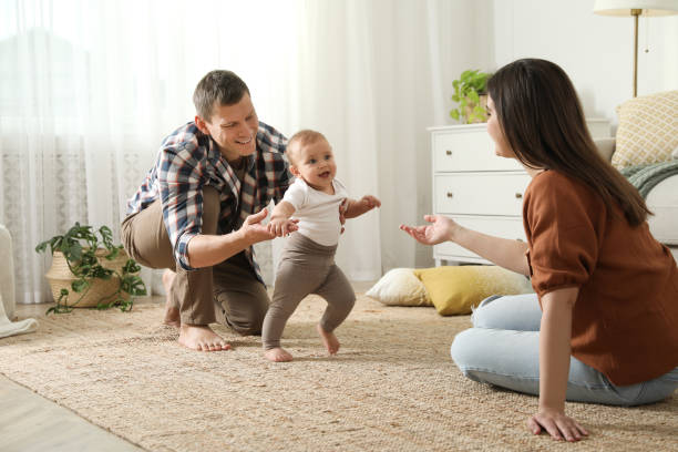 istock Parents supporting their baby daughter while she learning to walk at home 1445191845