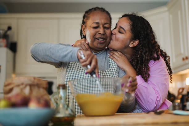 istock Happy african daughter kissing her mother while baking together inside kitchen at home 1445191971
