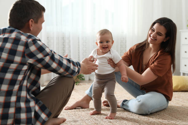 istock Parents supporting their baby daughter while she learning to walk at home 1445192002