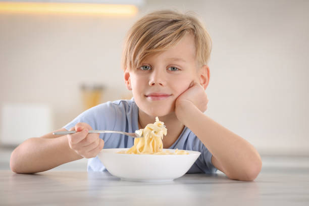 istock Happy boy eating tasty pasta at table in kitchen 1445192004