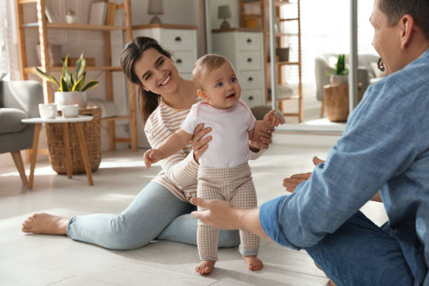 istock Parents supporting their baby daughter while she learning to walk at home 1445192011