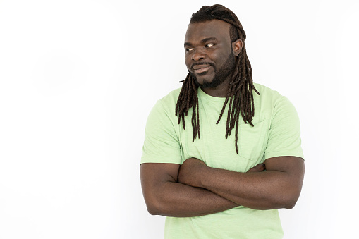 African American man with folded arms looking at copyspace. Handsome man in T-shirt promoting product while standing on white background. Advertising, promotion concept