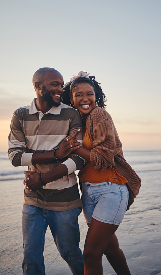 Happy, black couple, love and beach with smile for vacation in relationship together in the outdoors. African American man and woman enjoying bonding time on a ocean coast walk in South Africa