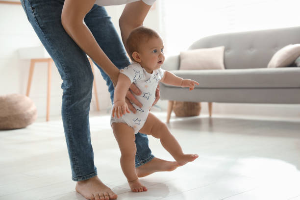 istock Father supporting his baby daughter while she learning to walk at home 1445192837