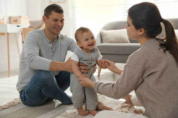 istock Parents supporting their baby daughter while she learning to walk at home 1445192861