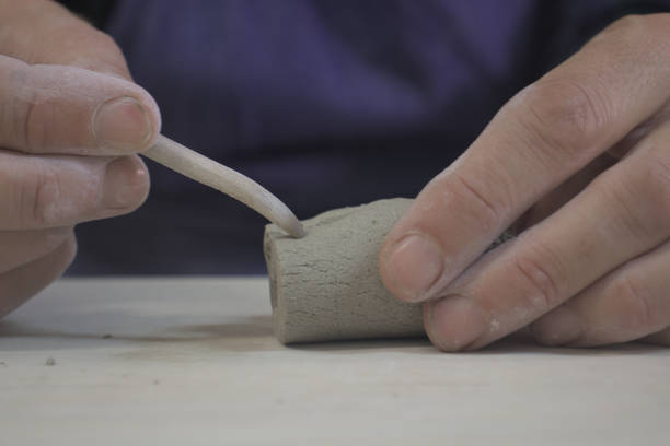 Very close-up on the hands of a ceramist engraving a piece of stoneware.
