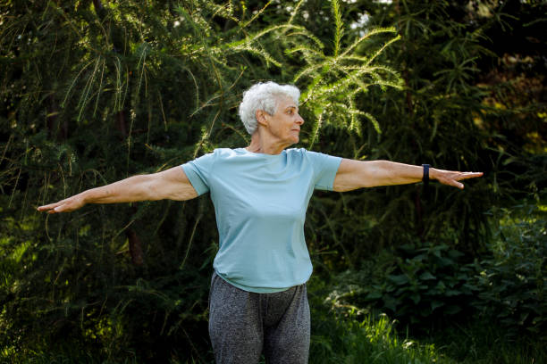 Mature woman relaxing in nature. Old woman meditating. Senior woman is doing yoga in the park. stock photo