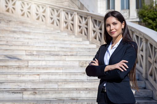 Portrait of a confident buisness woman with crossed arms standing in front at a staircase of a public building like courthouse or city hall