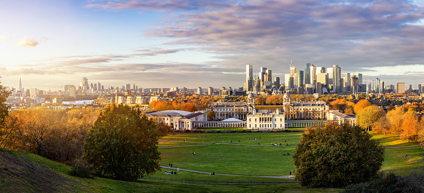 Panoramic view of the London skyline from Canary Wharf to the City seen from Greenwich Park during golden autumn sunset time
