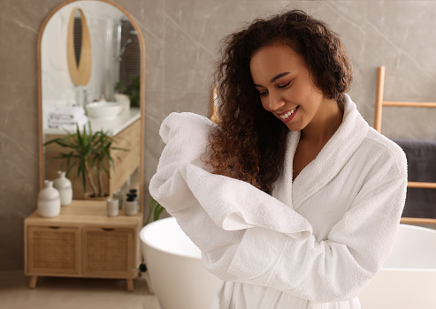 Beautiful African American woman drying hair with towel in bathroom