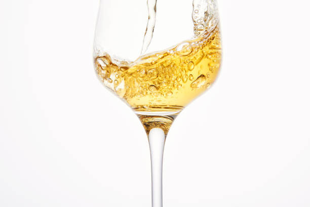 istock Stream of white wine flows into stem glass, swirls. 1445195062
