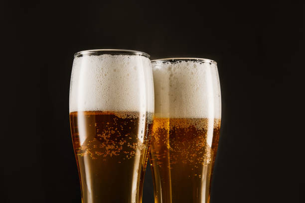 birra dorata con schiuma, bolle che riempiono bicchieri alti. - beer bottle beer drinking pouring foto e immagini stock