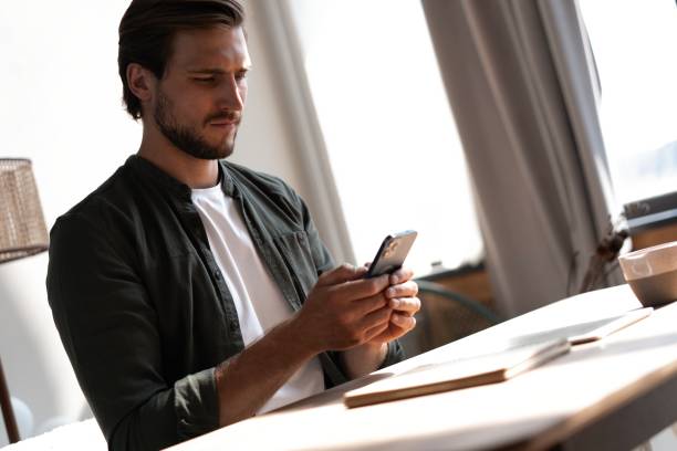 istock Young employee at workplace using mobile phone, checking social media on smartphone, taking break, copy space. 1445196728
