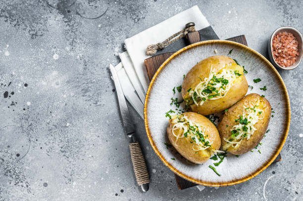 Baked Jacket potatoes with cheese and butter. Gray background. Top view. Copy space Baked Jacket potatoes with cheese and butter. Gray background. Top view. Copy space. baked potato stock pictures, royalty-free photos & images