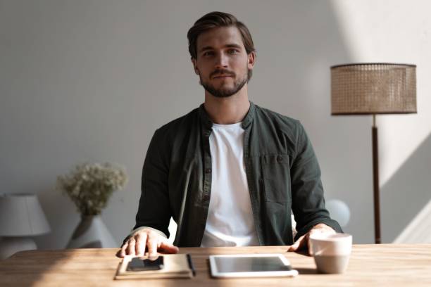 istock Good-looking millennial office employee sitting at desk smiling looking at camera 1445197215