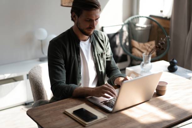 istock Male remote working from home and having work confrence video call. Freelancer working on laptop at home office. 1445197246