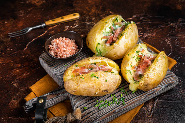 istock Jacket potatoes baked with cheese, herbs and butter. Dark background. Top view 1445197749
