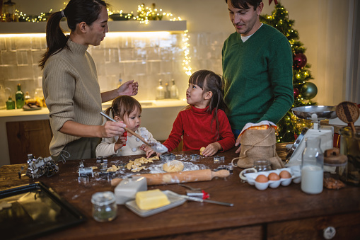 Photo of young family baking Christmas cookies during Christmas holidays.