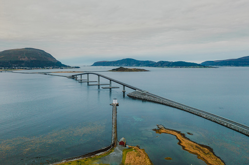 Drone photo of the modern bridge above the Norwegian Sea surrounded by the white lighthouse and the islands in More og Romsdal, Scandinavia