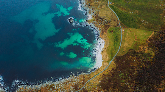 Drone high-angle photo of the bright yellow land and the turqouise sea in Møre og Romsdal, Scandinavia