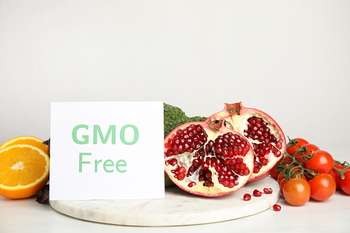 Tasty fresh GMO free products and paper card on white table