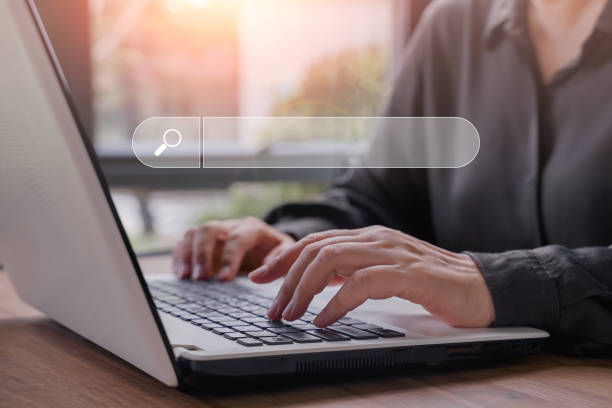 istock Hand of businessman searching, browsing internet data information with blank search bar. Search Engine Optimization SEO Networking Concept.Businesswoman working with computer laptop on desk in office. 1445199948