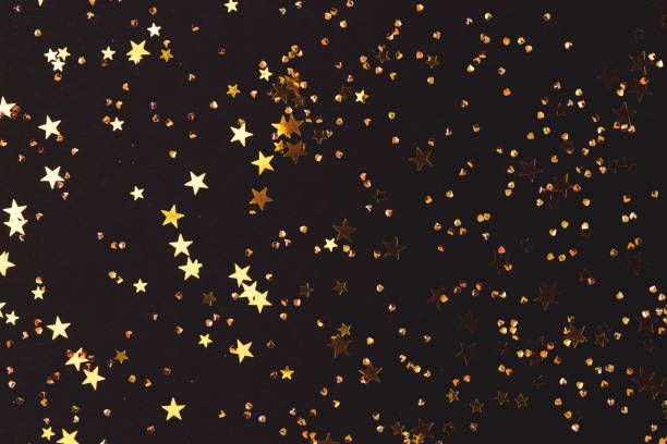 istock Glittering gold colored stars and crystals confetti on a black background. 1445200181