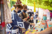 路上でアプリコットキャンディーを買う日本の伝統的な祭りの服を着た若い女性の友人
