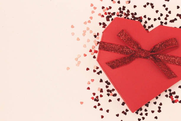 istock Red gift box in a heart shape tied with glittering ribbon. 1445201164