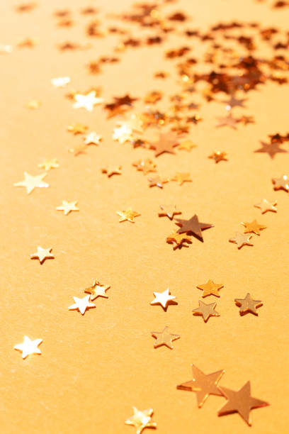 istock Shiny stars confetti scattered on a gold colored background. 1445201537