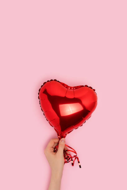 istock Hand hold red inflatable foil balloon in a heart shape. 1445201592