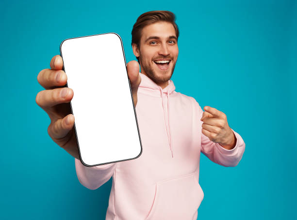 istock Handsome Excited Man Showing Pointing At Empty Smartphone Screen Posing Over Light Blue Background, Smiling To Camera 1445202134