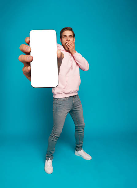 istock Handsome Excited Man Showing Pointing At Empty Smartphone Screen Posing Over Light Blue Background, Smiling To Camera 1445202144