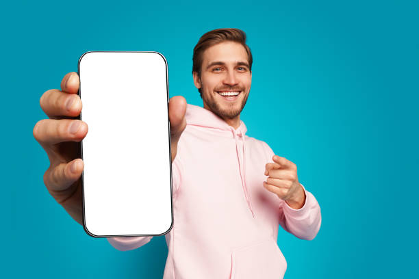 istock Handsome Excited Man Showing Pointing At Empty Smartphone Screen Posing Over Light Blue Background, Smiling To Camera 1445202146