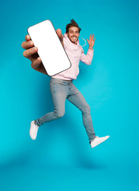 istock Handsome Excited Man Showing Pointing At Empty Smartphone Screen Posing Over Light Blue Background, Smiling To Camera 1445202160