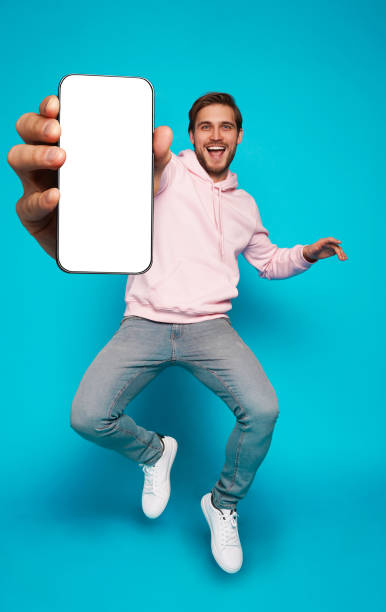 istock Handsome Excited Man Showing Pointing At Empty Smartphone Screen Posing Over Light Blue Background, Smiling To Camera 1445202198