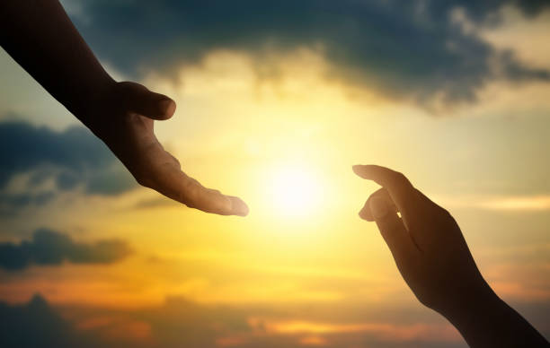 silhuetas de mãos estendendo a mão para a esperança e apoiando umas às outras no fundo do pôr do sol. - human arm praying out men - fotografias e filmes do acervo