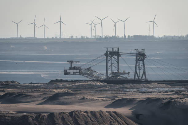 View of surface mine in Germany, heavy machinery in lignite mine and wind turbines in the background Garzweiler surface mine in Germany, view of the heavy machinery and wind turbines in the background open pit mining stock pictures, royalty-free photos & images