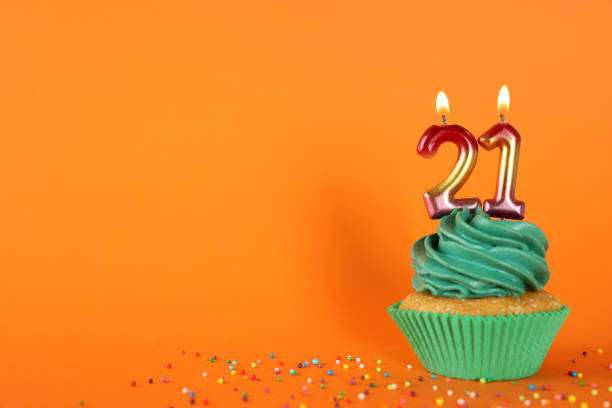 istock Delicious cupcake with number shaped candles on orange background, space for text. Coming of age party - 21th birthday 1445204701