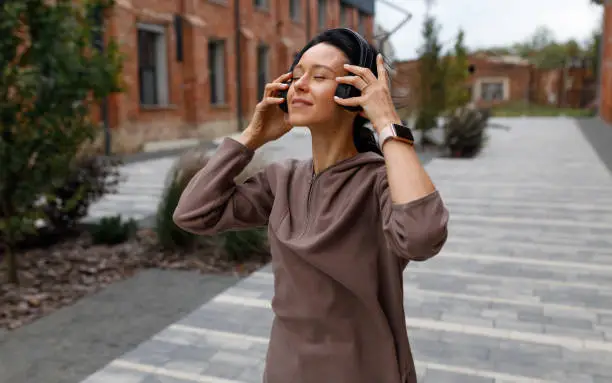 Photo of Woman puts on wireless headphones and enjoys songs and gets motivated before running around town