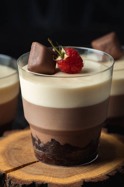 istock Layered dessert Trifles in a transparent glass.  Sponge biscuit and three chocolate mousse layers. Chocolate souffle trifle cake in individual disposable transparent cups. Black background 1445204817